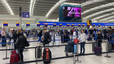 Passengers queue to check in at Heathrow Airport in London. PA