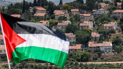 The Israeli settlement of Halamish behind a Palestinian flag raised for the funeral of Mohammed Haitham Al Tamimi, a three-year-old Palestinian boy shot by Israeli forces in the occupied West Bank. AFP