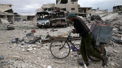 A man walks with his bicycle at a damaged site in the besieged town of Douma, Eastern Ghouta. Bassam Khabieh / Reuters