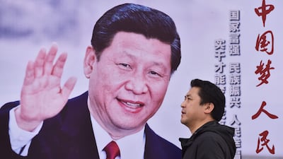 A man walks past a poster featuring Chinese president Xi Jinping with a slogan reading 'Chinese Dream, People's Dream' beside a road in Beijing on October 16, 2017. Greg Baker / AFP
