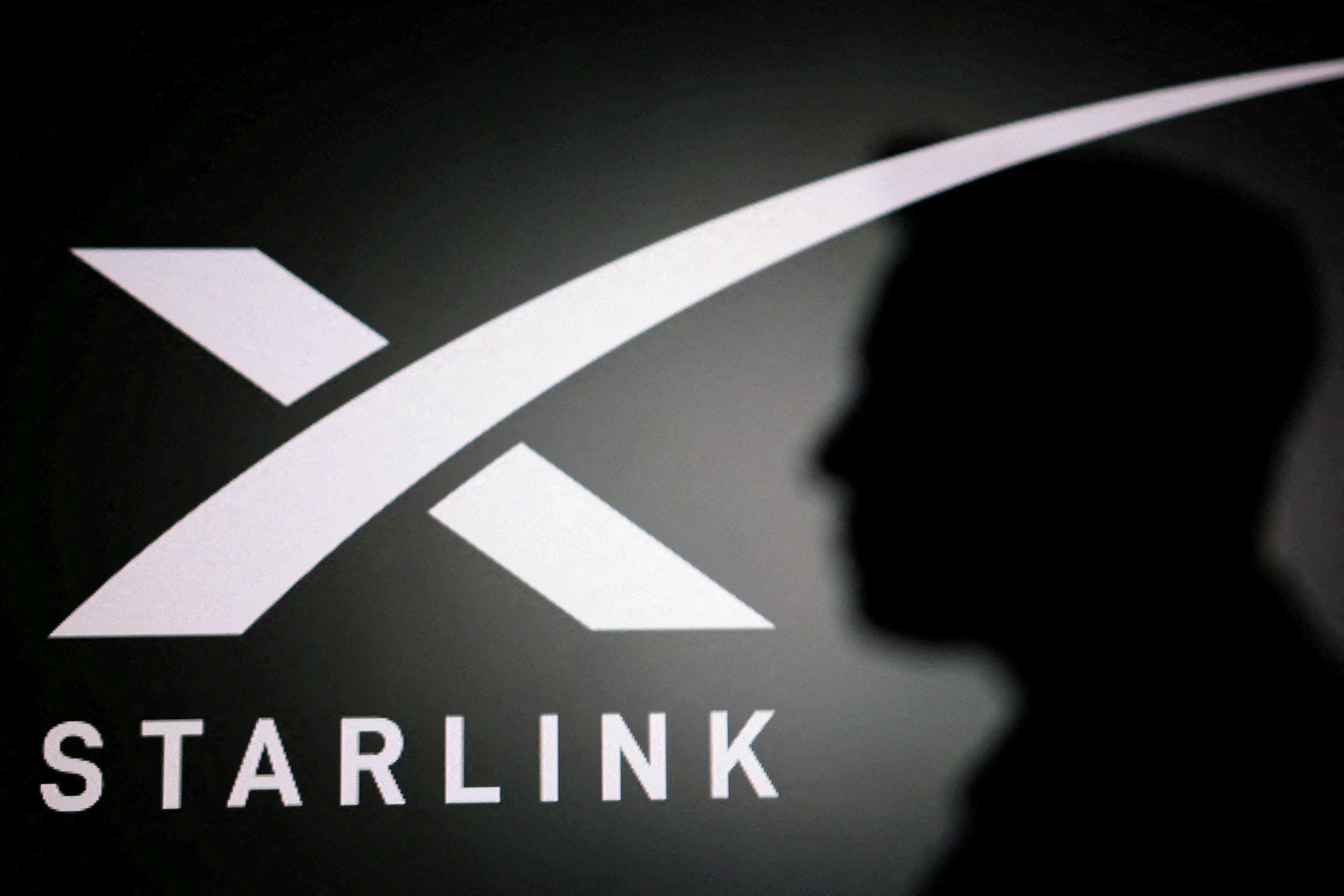 The silhouette of Elon Musk and the Starlink logo. Reuters