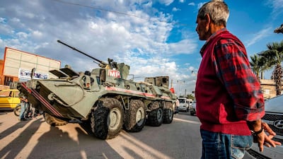 A man watches as a Russian military police armoured vehicle passes through a street in the northeastern Syrian town of Amuda. AFP