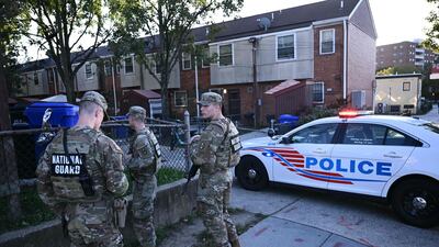 Members of the National Guard stay back as police officers and federal law enforcement agents investigate the scene of a shooting in southeast Washington. AFP