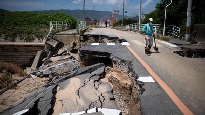 A man with a shovel walks on a damaged road in Mabi, Okayama. AFP