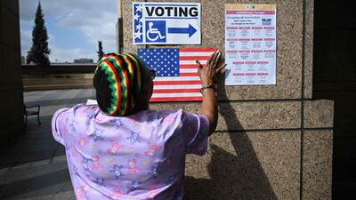 A poll worker hangs signs and a US flag outside a polling station during early voting ahead of the US midterm elections, in Los Angeles, California, on November 1. AFP