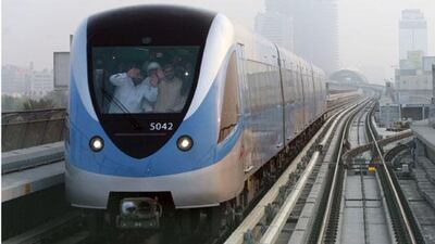 Passengers wave from a passing train seen from on board the first train of the day on the Dubai Metro network which pulled out of the Nakheel Harbour & Tower station at 6am in Dubai on September 10, 2009.