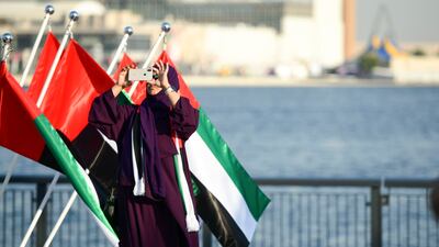 A visitor take photos against a backdrop of UAE flags