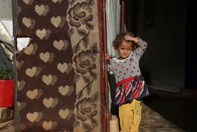 A displaced Syrian child in an encampment in northwestern Syrian stands outside a tent in the village of Harbnoush. AP
