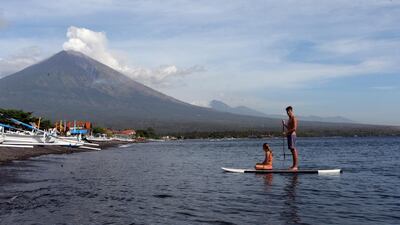 Tourists paddle their board as they watch Mount Agung spew ash and smoke in Karangasem, Bali, Indonesia. Firdia Lisnawati / AP Photo
