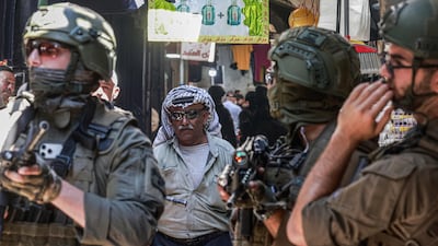A Palestinian man walks past Israeli soldiers in Nablus, in the northern Israeli-occupied West Bank. AFP