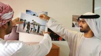 The Tawteen team leaders Saoud Karmastaji, left, and Hamad al Zaabi with photos taken at a camp for integrating Emiratis into the private sector.