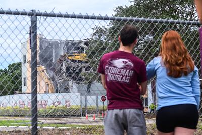 People watch as crews begin to demolish the building where 17 people were killed during the 2018 mass shooting at Marjory Stoneman Douglas High School in Parkland, Florida. AFP