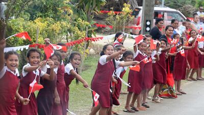 Tongan school children wave flags along the procession. Getty Images