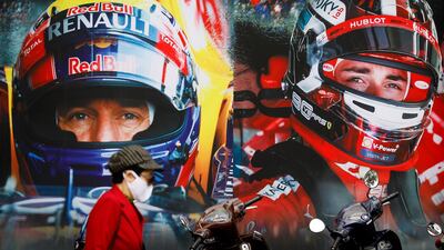 A woman wearing a protective mask walks past a Formula One Vietnamese Grand Prix merchandise store in Hanoi, Vietnam. EPA