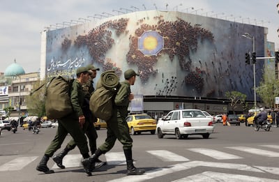 Iranian soldiers walk next to a huge banner bearing a sentence reading 'Stay steadfast on this path' in a street in Tehran. EPA
