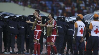 Police shield themselves as Equatorial Guinea's Raul Fabian Bosio, left, and Igor Engonga Noval, appeal to supporters to stop throwing object onto the pitch during their African Cup of Nations Semifinals soccer match with Ghana at Estadio De Malabo, Equatorial Guinea, Thursday Feb. 5, 2015. (AP Photo/Sunday Alamba)