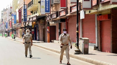 Police personnel patrol along a street during the weekend lockdown in Amritsar, Punjab. Economists say the impact of local lockdowns will not be as severe as last year. AFP