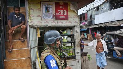 Sri Lankans stand near a roadside shop as a Naval soldier stand near the damaged St Anthony's Church, in Colombo. AP Photo