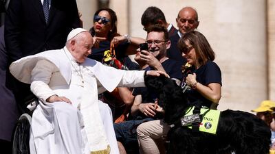 Pope Francis pets a dog after the weekly general audience in St Peter's Square at the Vatican. Reuters