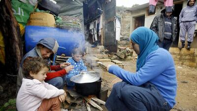 A Syrian refugee and her children prepare food in the Chouf mountain town of Ketermaya, Lebanon. The U.N. World Food Program says it has suspended a food voucher program serving more than 1.7 million Syrian refugees because of a funding crisis. (AP Photo/Mohammed Zaatari, File)