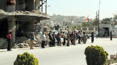People stand in front of a destroyed building, in an unspecified town in Aleppo province, northern Syria, on April 18, 2018. EPA
