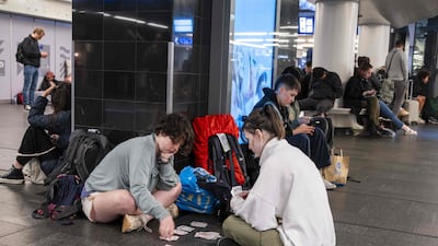 Travellers play cards as they wait for their train at Amsterdam Central Station. AFP