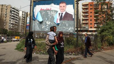 People walk past a torn campaign banner, ahead of parliamentary election that are scheduled for May 15, in Tripoli. Reuters