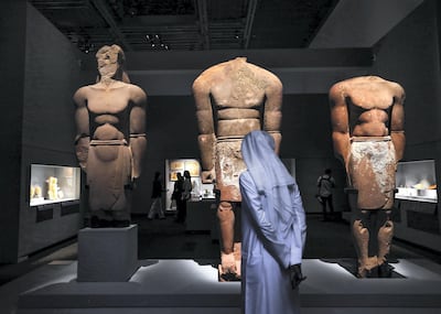 A visitor looks at the three colossal human statues that were uncovered at Dedan in Arabia's north-west. Victor Besa / The National