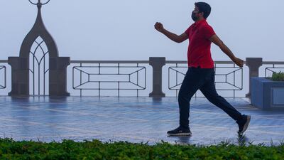 A man strides out on a gloomy Corniche. Victor Besa / The National