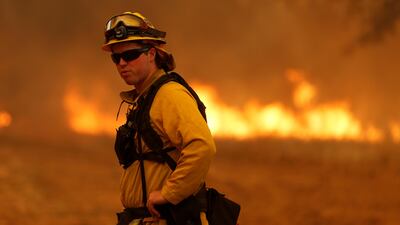 A firefighter stands near a grass fire as he prepares to defend a home from the Detwiler fire in Mariposa, California. Stephen Lam / Reuters