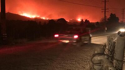Flames are seen behind Carpinteria, California. Mike Eliason / Santa Barbara County Fire Department via AP