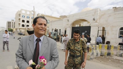 The spokesperson for the Baha'i community in Yemen, Abdullah Al Olufi, holds flowers as he stands outside a state security court during a hearing in the case of a Baha'i man charged with seeking to establish a base for the community in Yemen, in the country's capital Sanaa on April 3, 2016. Reuters.