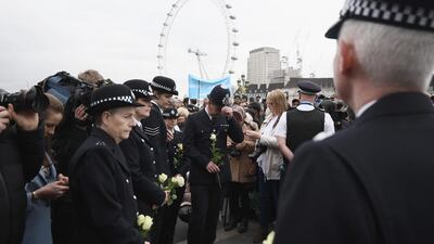 Police officers carry a single flower on Westminster Bridge during a vigil to remember the victims of last week's Westminster terrorist attack in London. Carl Court / Getty Images