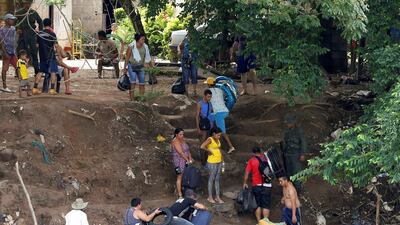 People carry goods past soldiers as they disembark from a boat at Boca del Grita in Venezuela after crossing the border from Colombia. Carlos Garcia Rawlins/Reuters