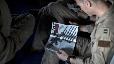 A pilot reads a specialised weapons magazine as he sits on board the USS Theodore Roosevelt.