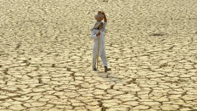 An Indian man carries a clay pitcher of water on his head as he crosses parched land on a hot day at the village Bhunerheri, some 12 kms from Patiala. Sultry conditions and high humidity levels prevailed as temperatures hovered in the region of 38 degree Celsius. AFP