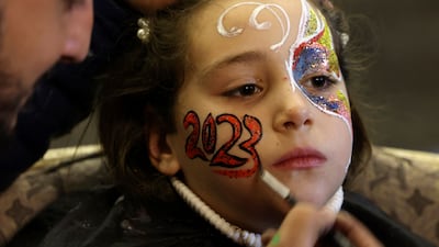 An artist paints 2023 on the face of a Palestinian girl ahead of New Year's celebrations, in Gaza City. AFP