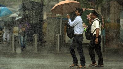Indian pedestrians carry umbrellas as they walk through heavy rain showers in Mumbai on July 13, 2017. AFP / Punit Paranjpe