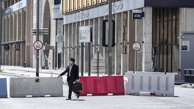 A pedestrian walks past barricades on Baniyas Road just hours before the 24-hour stay-home order was lifted in Al Ras and Naif on Sunday night. All photos by Antonie Robertson / The National