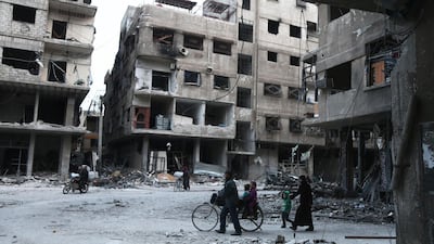Syrians walk past destroyed buildings in Arbin in the rebel-held enclave of Eastern Ghouta on February 25, 2018. Abdulmonam Eassa / AFP