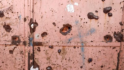 Pupils peep through shrapnel holes in the school gate. AFP