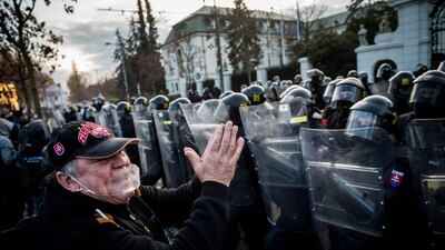 A man gestures in front of anti-riot police during a protest involving hundreds of football hooligans and far-right voters of Kotleba's LSNS party against the government's measures to curb the spread of Covid-19, at the Government Office in Bratislava. AFP