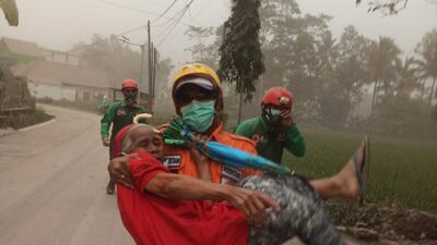 A rescuer helps an elderly resident following the eruption of Mount Semeru. Reuters