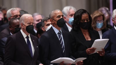 US President Joe Biden, former US president Barack Obama and former first lady Michelle Obama hold hymn sheets. AFP