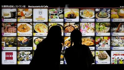 Women look at restaurant advertisement boards in central Tokyo. A planned sales tax rise has been put on hold by the government, concerned at persistently low consumer spending. Toru Hanai/Reuters