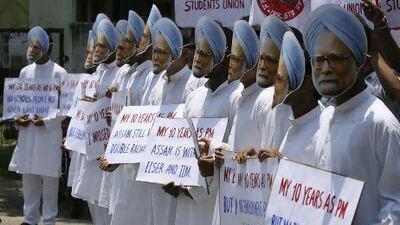 Demonstrators wearing masks of India's prime minister Manmohan Singh hold placards during a protest in Guwahati.
