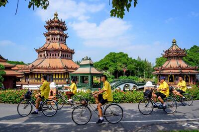 Schoolchildren ride bicycles past the Ancient City Heritage Park in Samut Prakan. AFP