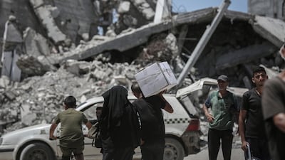 A Palestinian man carries an Emirates Red Crescent food box from an aid distribution centre in Gaza city. Bloomberg
