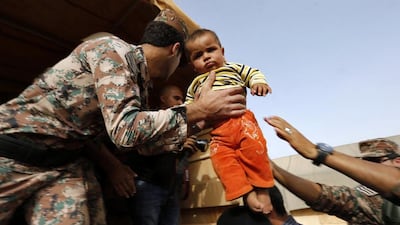 A Jordanian soldier helps a Syrian refugee family to board an army vehicle in Al Ruqban border area. Muhammad Hamed / Reuters