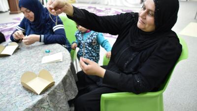 A woman examines her handiwork on the charity charm bracelets created by the camp's members for MKS Jewellery